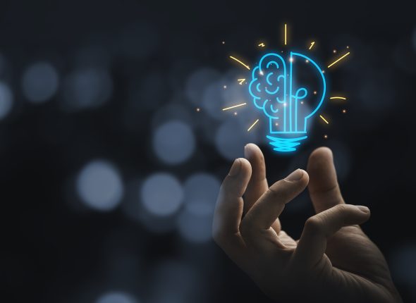 Hand holding drawing virtual lightbulb with brain on bokeh backg